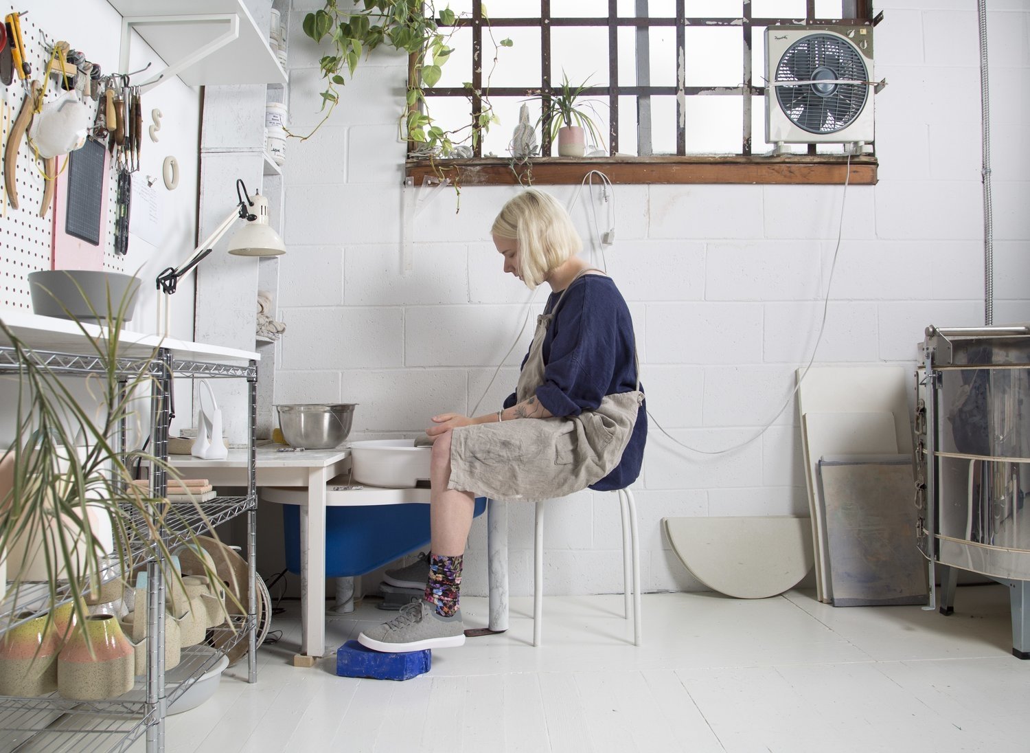 Woman with apron sitting on stool making pottery