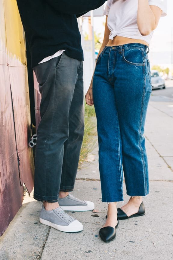 Guy wearing grey sneakers stands in front of girl wearing denim and black flat shoes